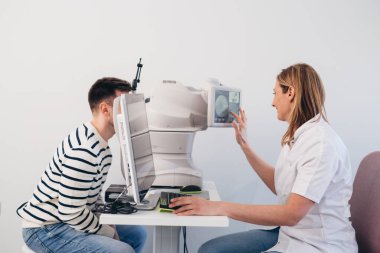 Kafkasyalı yetişkin bir adamın doktor muayenehanesindeki retina tarayıcısında görüş kontrolü var.