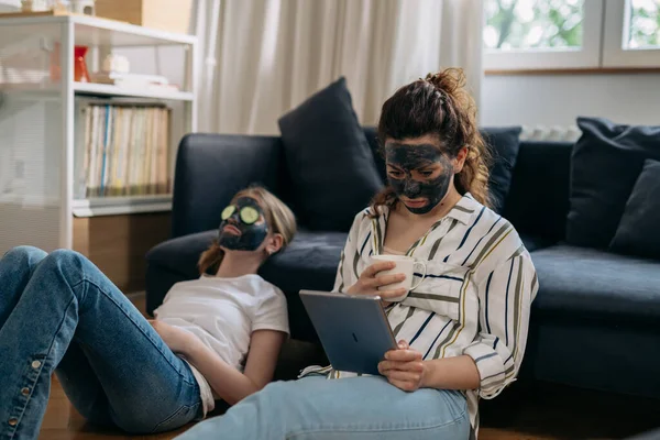 Mother Daughter Cosmetic Face Masks Faces Mother Using Digital Tablet — Zdjęcie stockowe