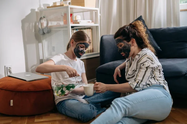 mother and daughter talking at home. they puts cosmetic face mask on their faces