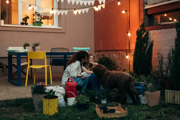 full length body shoot of mother and daughter gardening in backyard. they are hugging