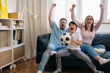 one child family cheering and watching soccer game at home