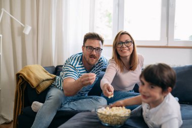 Evde film izlerken patlamış mısır yiyen sevimli bir aile.