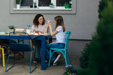 Kafkasyalı anne ve kız evlerinin arka bahçesinde kahvaltı yapıyorlar.