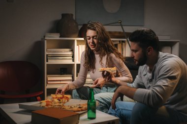 Evde pizza yiyen genç bir çift.