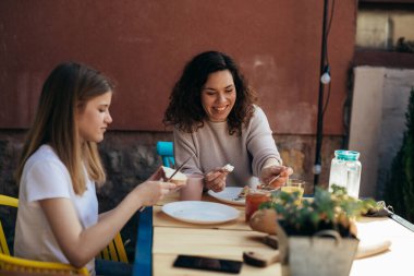 Anne ve kızı evlerinin arka bahçesinde kahvaltı ediyorlar.
