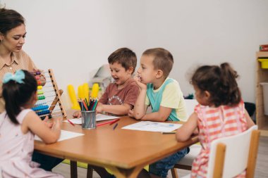 Öğretmen ve çocuklar sınıfta abaküs hesaplamayı öğretiyor.