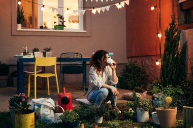 Kadın bahçesinde rahat bahçeli çiçekler hissediyor. Akşam sahnesi