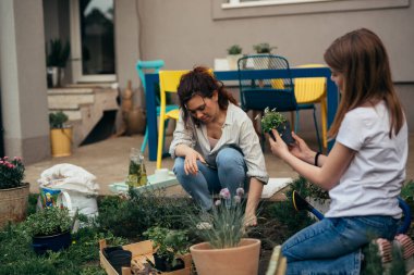 Anne ve kızı arka bahçede bahçeyle uğraşıyorlar.