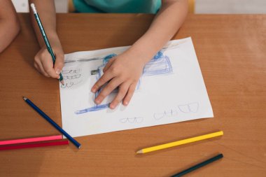 Şirin bir çocuk ve evde kağıt üzerine kalem çizen bir çocuk.