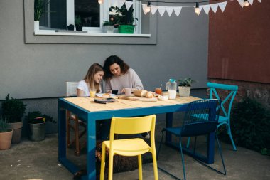 mother and daughter breakfast together at home. they checking social media on mobile phone