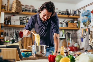 caucasian young man preparing spaghetti in kitchen
