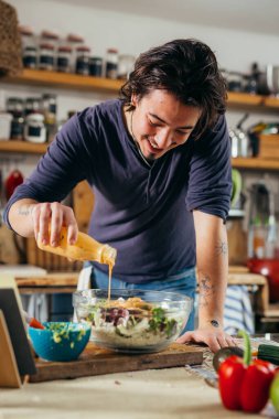 Genç adam mutfağında salata hazırlıyor.