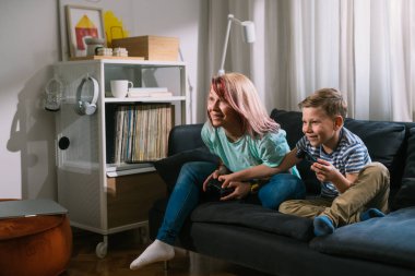 Anne ve oğlu evde video oyunu oynuyorlar.