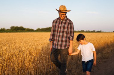 father and son walking through wheat field