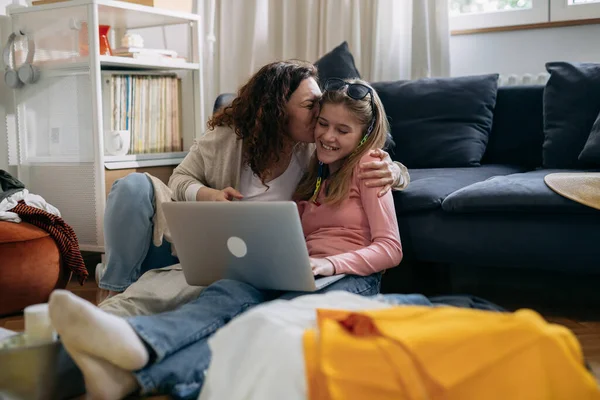 mother kisses her daughter while packing bags for summer vacation