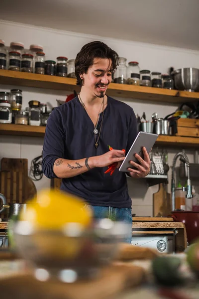 man looking for recipes on digital tablet. preparing food in his home kitchen