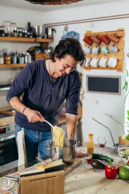 Adam evde makarna hazırlıyor.