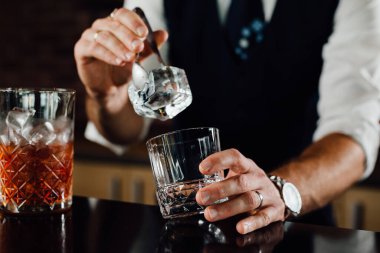 close up bartender adding ice in glass