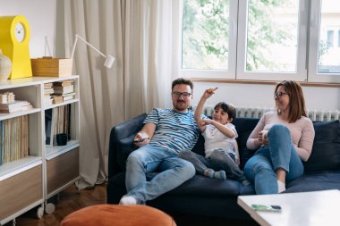 family watching television sitting on a sofa in living room