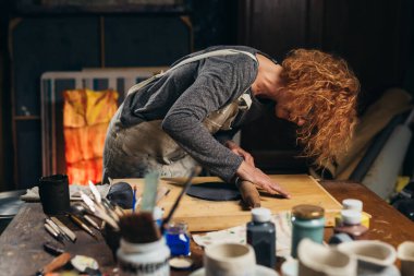 woman molding clay in her workshop