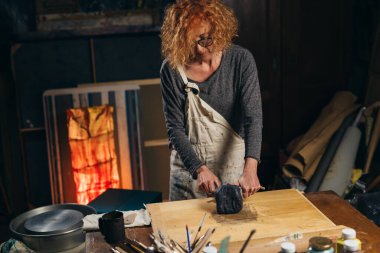 woman cuts clay. making pottery in her atelier