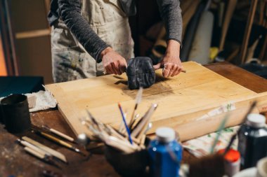 close up of woman cuts clay. making pottery in her atelier