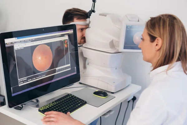 Adam klinikteki retina tarayıcısında göz görüşünü kontrol ediyor.