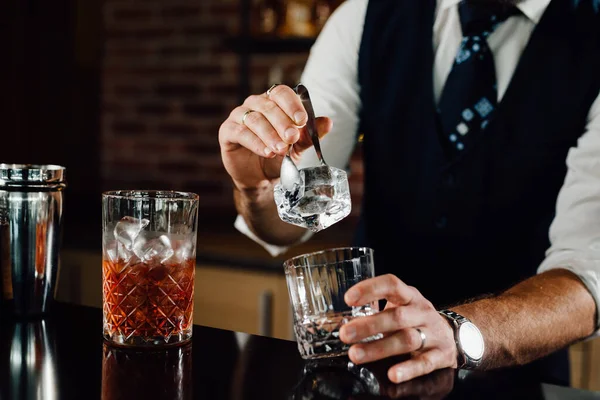 close up of barmen adding ice in glass