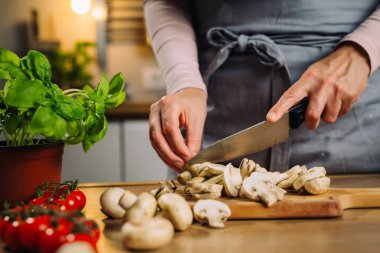 woman slice with knife mushrooms in kitchen