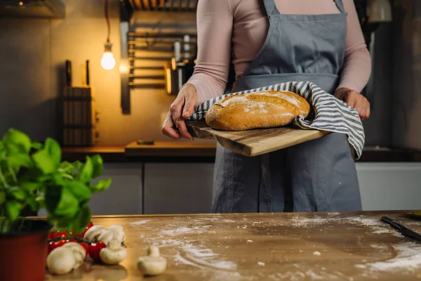 woman holding baked loaf of bread in her home kitchen
