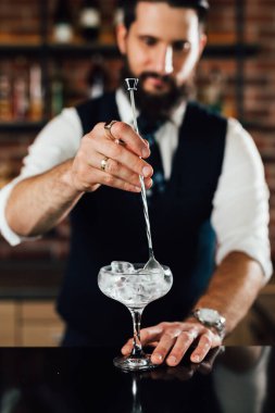 Barmen bardağını buzla soğutuyor.