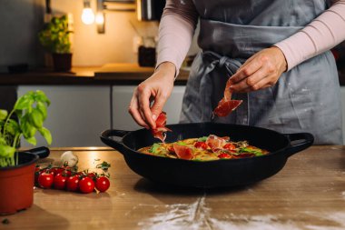 woman add ham to pizza. preparing pizza in home kitchen