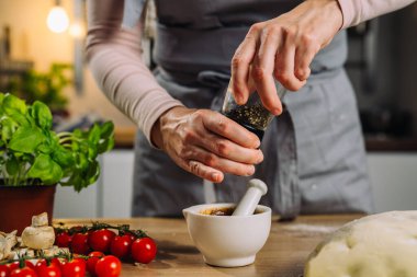 close up of woman spicing pizza dressing