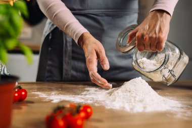woman pouring flour on kitchen table. preparing dough for bread or pizza