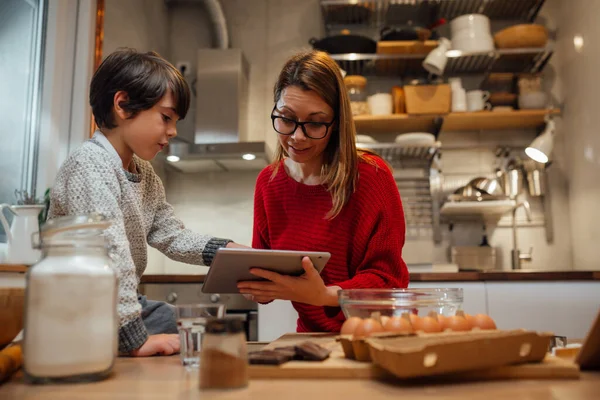 mother and son searching for recipes on digital tablet in kitchen