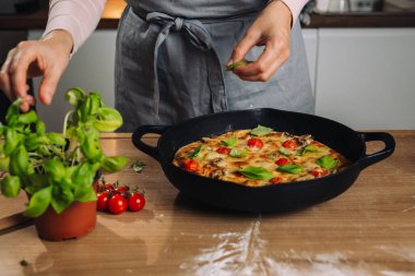 Pizza süslemek için fesleğen toplayan kadına yaklaş.