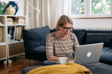 Oturma odasında dizüstü bilgisayar kullanan bir kadın.