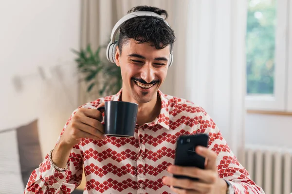 Lächelnder Mann Trinkt Kaffee Und Benutzt Handy Drinnen — Stockfoto