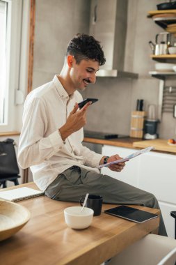 Genç işadamı evde cep telefonuyla konuşuyor.