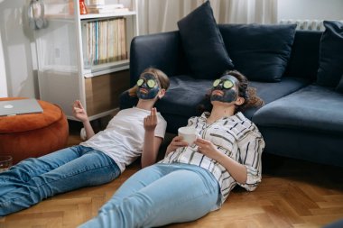 Anne ve kızı uygulamalı kozmetik maskeyle evde dinleniyorlar.