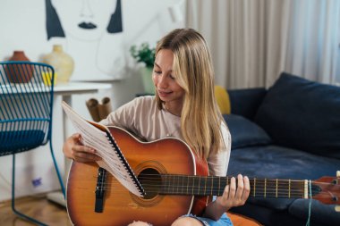 Avrupalı genç kız evde akustik gitar çalıyor