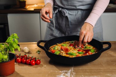 Kadın mutfakta ev yapımı pizza hazırlıyor.