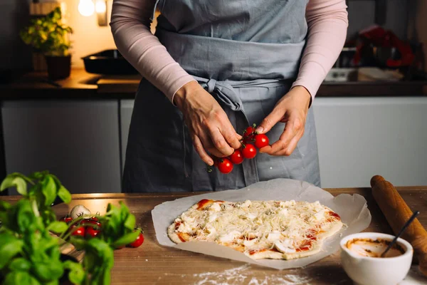 woman prepares home made pizza in kitchen