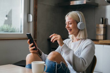 Kafkasyalı genç bir kadın sabah kahvesini içiyor ve evde video görüşmesi yapıyor.