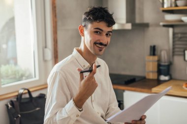 Genç işadamı mutfakta cep telefonuyla konuşuyor.