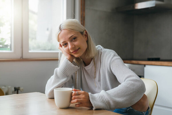 gen z female drinking morning coffee in kitchen
