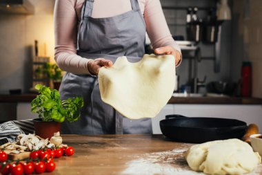 Ev mutfağında pizza için hamur hazırlayan kadına yaklaş.