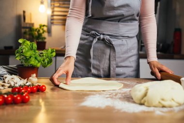 Ev mutfağında pizza için hamur hazırlayan kadına yaklaş.