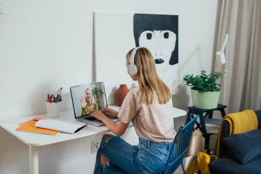 Bayan öğrenci odasında oturuyor ve video görüşmesi yapıyor.