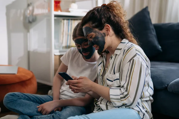 mother and daughter skin cleansing using clay face mask